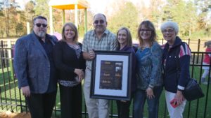 People standing in front of the playground holding a plaque.