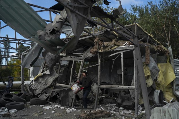 A man carries a bucket of water to extinguish the remains of a fire in the remains of a car shop that was destroyed after a Russian attack in Zaporizhzhia, Ukraine, Tuesday, Oct. 11, 2022. Russia has declared its intention to increase its targeting of Ukraine’s power, water and other vital infrastructure in its latest phase of the nearly 8-month-old war. (AP Photo/Leo Correa, File)