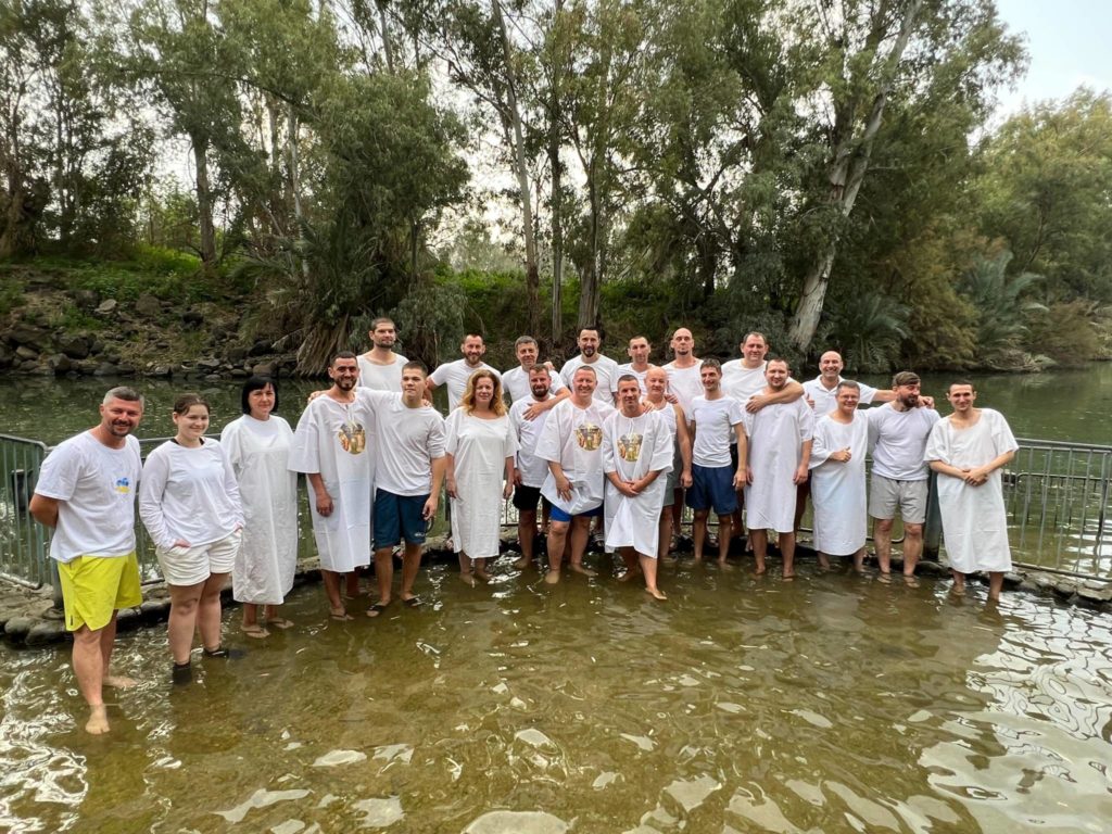 men and women from feeding program standing in the Jordan River after water baptism