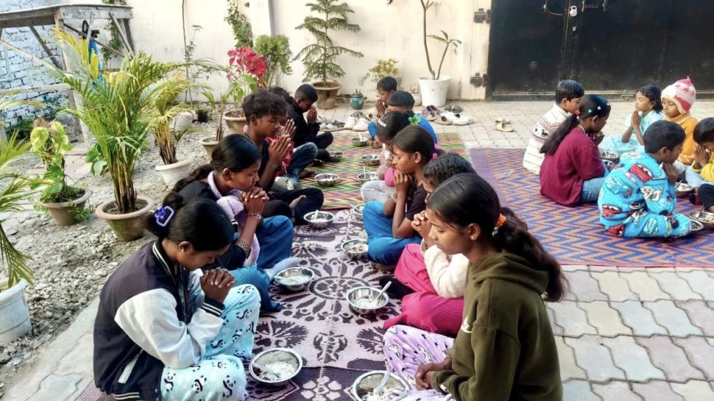 A group of children sitting on the ground eating food
