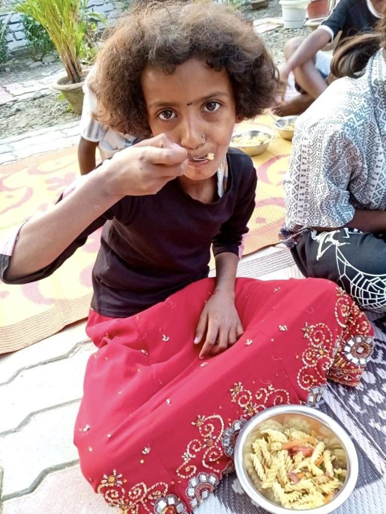 a girl sitting on the ground eating food